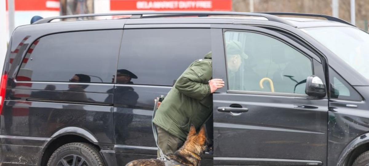 Беларуский пограничник проверяет автомобиль со служебной собакой в пункте пропуска «Брест»