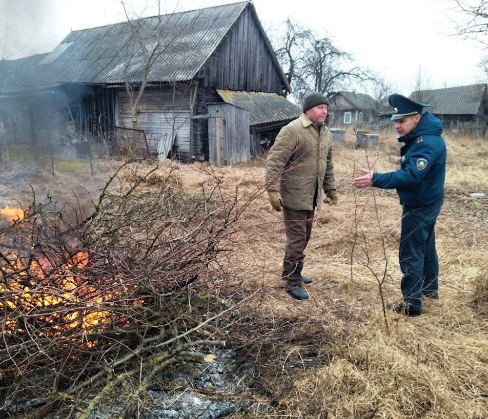 Сотрудник МЧС показывает на костер и рассказывает хозяину подворья о правилах сжигания сухой растительности в агрогородке Яечковичи Бродницкого сельсовета Ивановского района. Фото: МЧС.