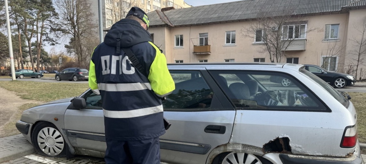 В Барановичах гаишник изучает заброшенный автомобиль. Фото: "Наш край"