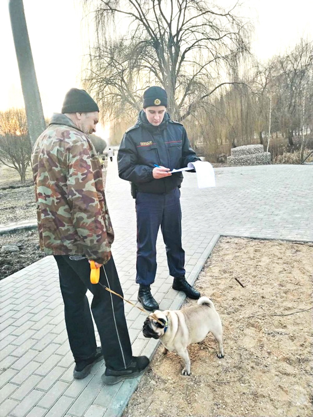 Участковый во время рейда в Барановичах напоминает хозяину пса о правилах выгула. Фото: «Наш край».