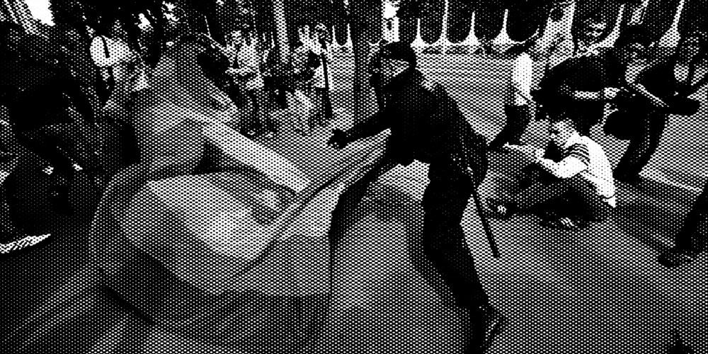 Силовик в форме ОМОНа задерживает человека на улице, рядом другие задержанные. Сцена связана с давлением на ЛГБТК-сообщество.