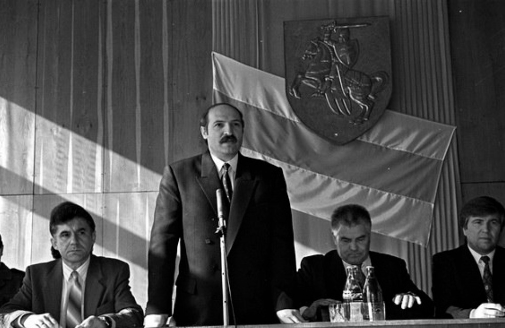Александр Лукашенко в 1990-х на фоне БЧБ-флага и герба Пагоня